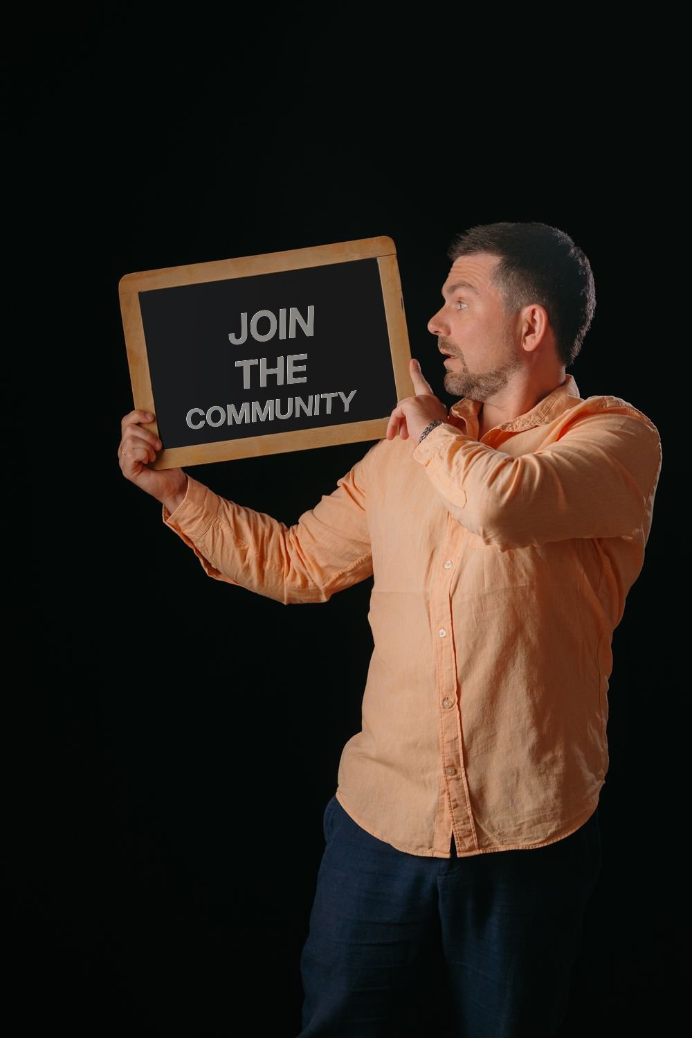 Sam Musayev holding a blackboard that reads Join the Community