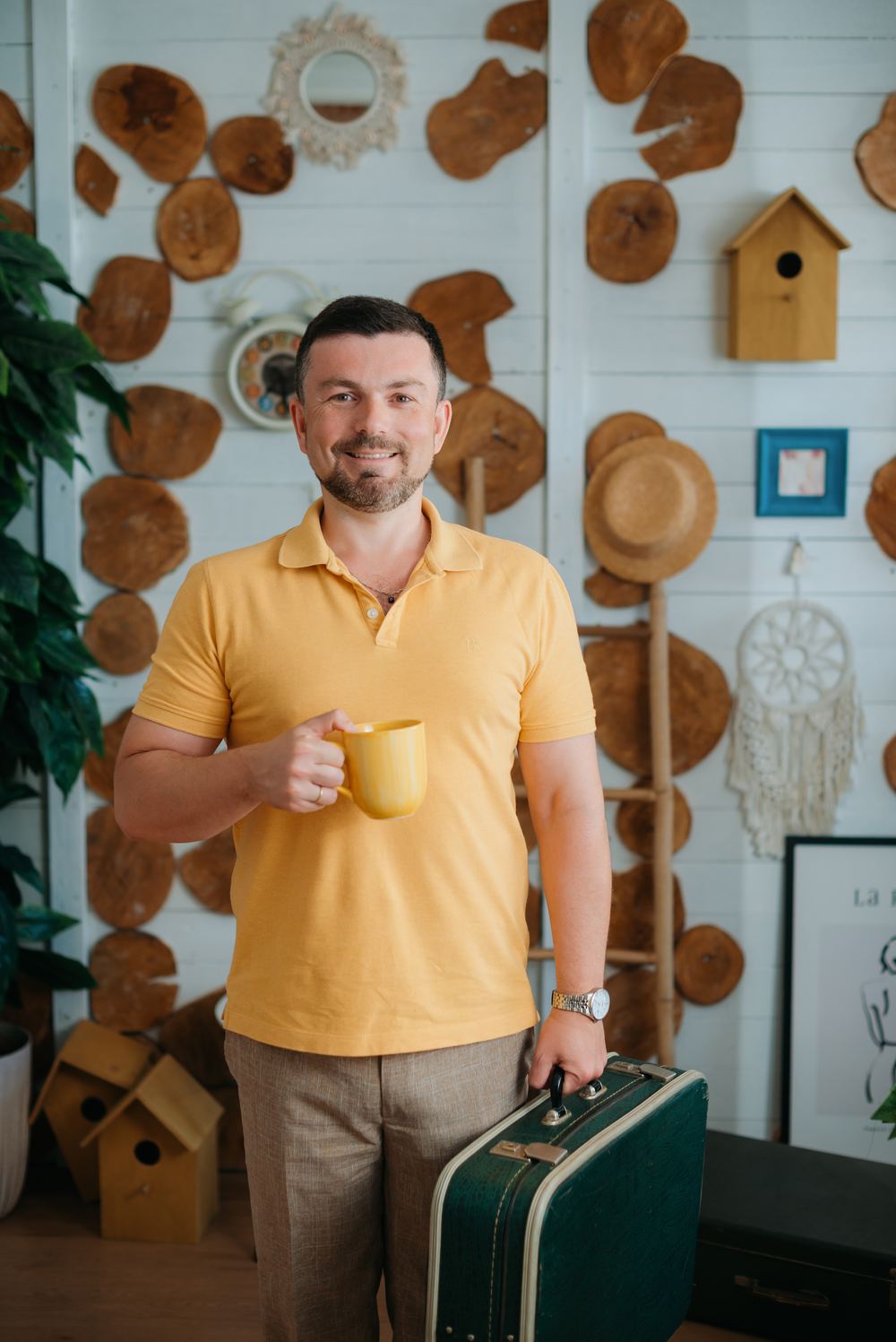 Sam Musayev holding a coffee mug and a vintage suitcase